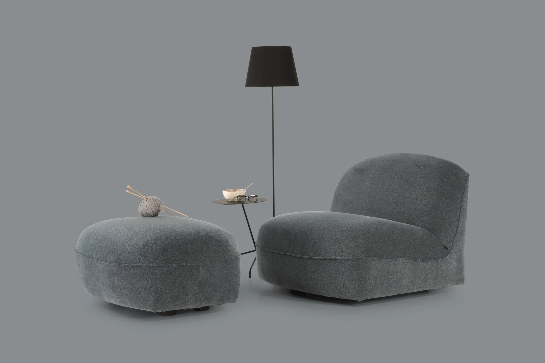 A picture of an elegant, curved chair in grey, with matching ottoman